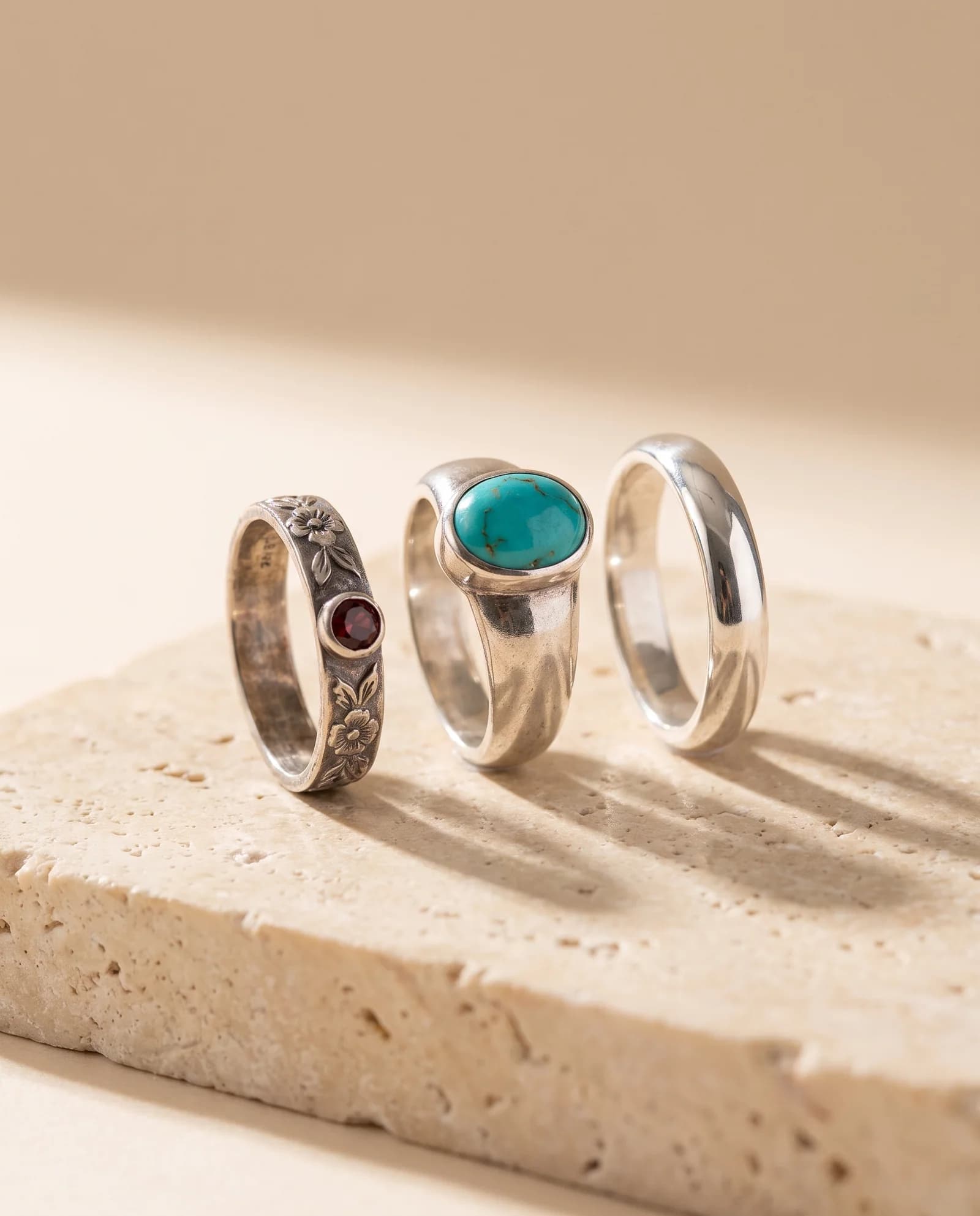Three sterling silver rings standing on a travertine slab