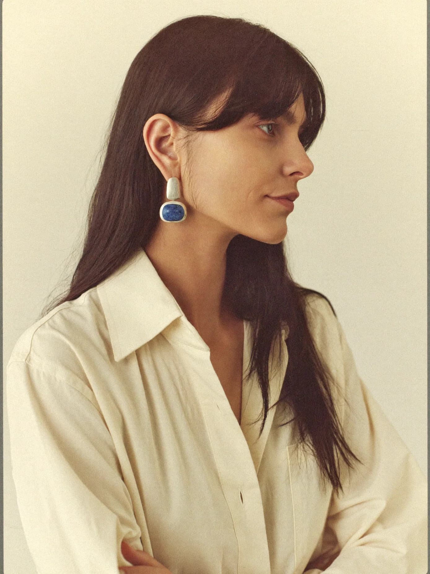 Profile of a woman wearing a silver drop earring with a lapis lazuli stone